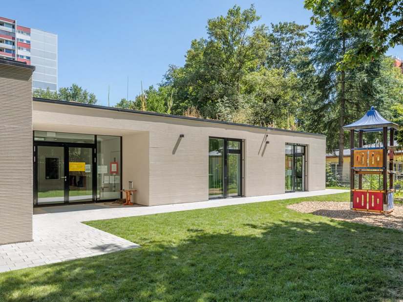 De nieuwe uitbreiding is een aanvulling op het ensemble van kerk, pastorie en bestaande kleuterschoolgebouw.