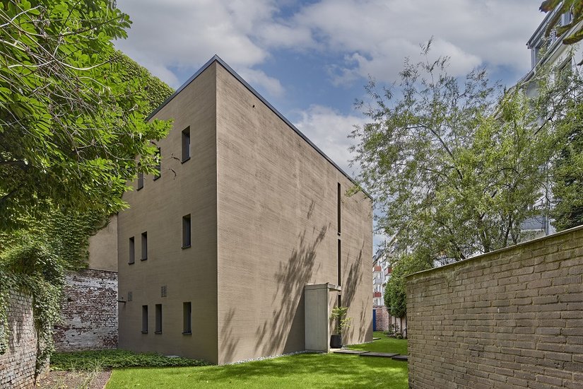 Op een bochtig restperceel in het midden van de stad werd het alomtegenwoordige ruimte- en woonprobleem exemplarisch opgelost. Aan de goed geproportioneerde monolithische westzijde, die slechts voorzien is van deurelementen en lichtvoegen, speelt de gevelvormgeving de hoofdrol.