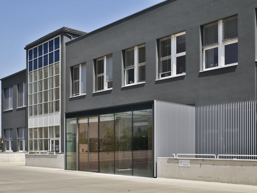 De metalen relingen aan de ingang werden met witte aluminiumlak in RAL 9006 omgevormd tot een wondermooie onderbreking in de look van dit twee verdiepingen tellende gebouw.