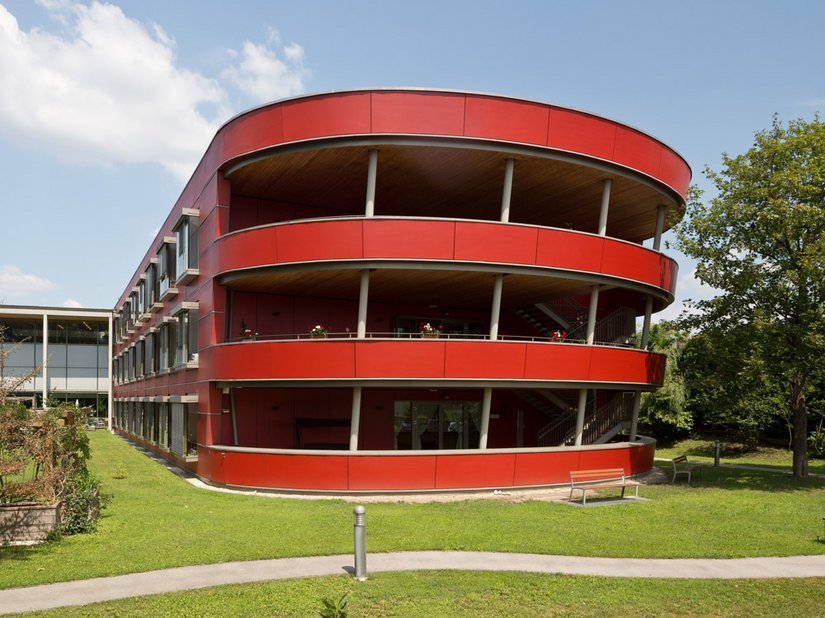 De ark valt op door zijn pittige rode kleur (RAL 3013 tomatenrood) tussen het groen van het omliggend park.