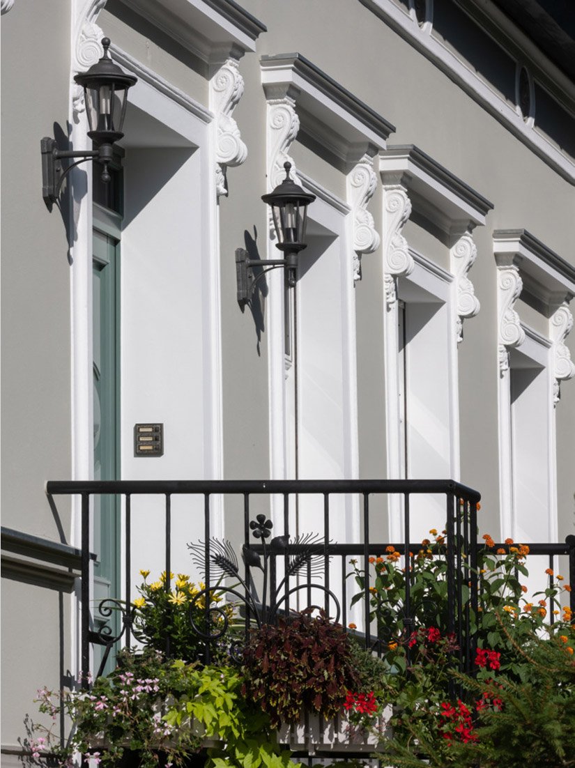 De verdeelde vensters, de opnieuw opgevulde en omlijste pilasters en kroonlijsten geven het kleine huis een bijna adellijke buitenkant en een nieuwe zichtbaarheid.