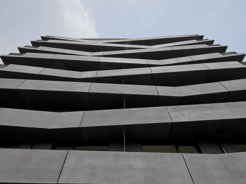 De als tweede gevellaag boven de sierbetonzuil uitstekende balkons versterken de indruk van een prettig soort gewichtloosheid.