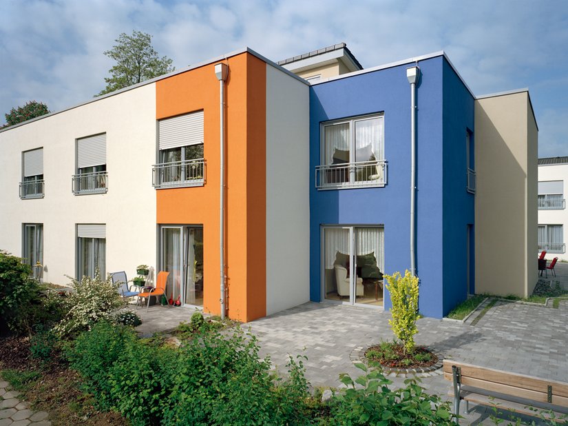 Het rijke oranje en het gedempte blauw fleuren het voor de overige wit en vanillekleurige gebouwschil op. De getrapte architectuur, de rechthoeken en afmetingen komen tot leven.