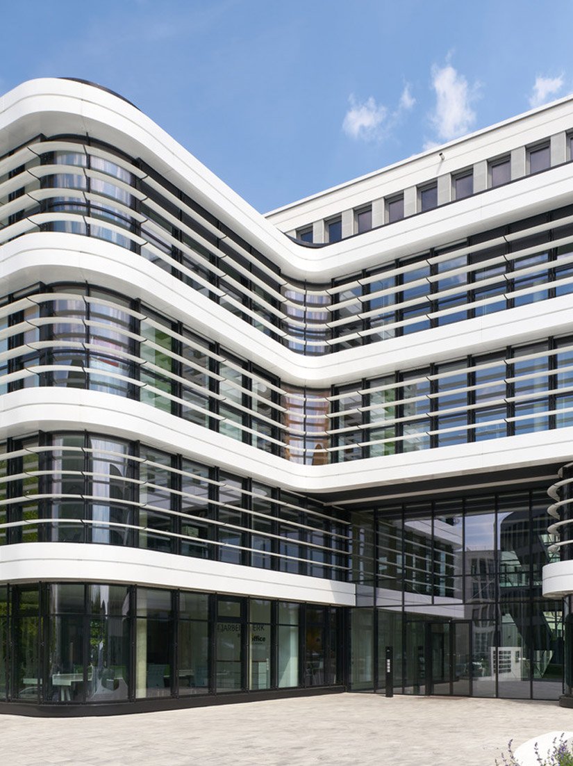 Architectonische hoogtepunten zijn het centrale trappenhuis met zijn royale atrium in sierbetonconstructie en de gebogen witte gegroefde zuilengevel met zijn omringende schaduw en karakteristieke vleugelprofielen.