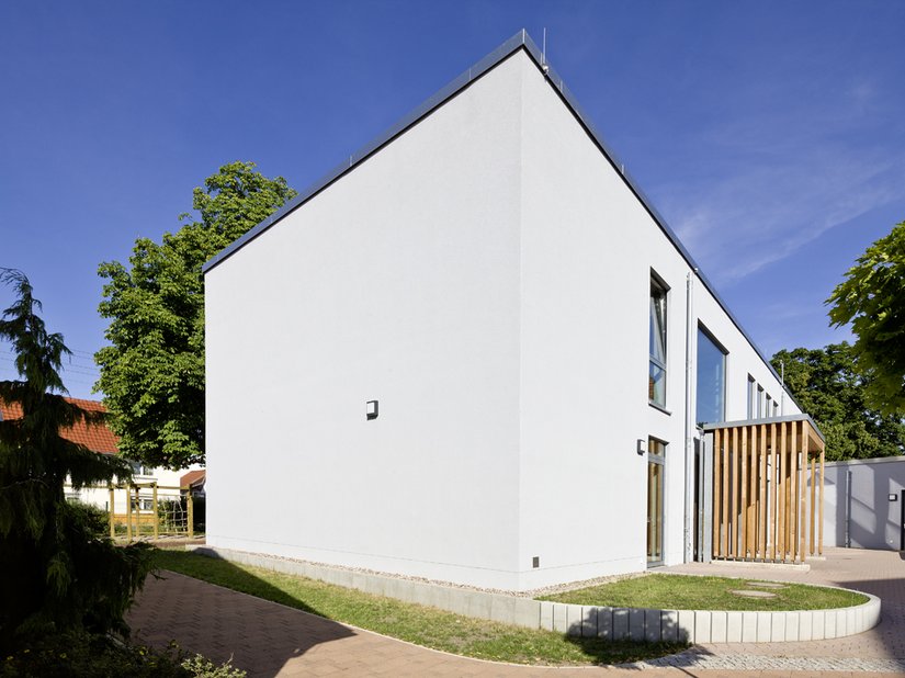 Het houtwerk aan de ingang absorbeert de kleur van het naastgelegen gebouw.