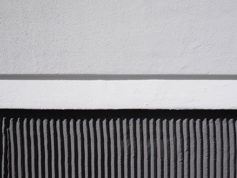 Het feit dat de donker gecontrasteerde gepleisterde basis bovendien is ontworpen met een verticale tandlijst is een ander opmerkelijk detail van het ontwerp.