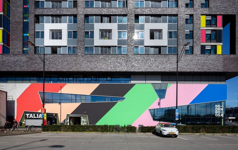 Een ontwerp met een boodschap: Tien lichtgevende kleuren in diagonale richting kenmerken nu de sokkelverdiepingen vanuit alle kijkrichtingen. De vroegere grijze kelderverdieping fungeert nu als een grafisch podium, dat tolerantie, openheid en creatieve energie zichtbaar maakt.