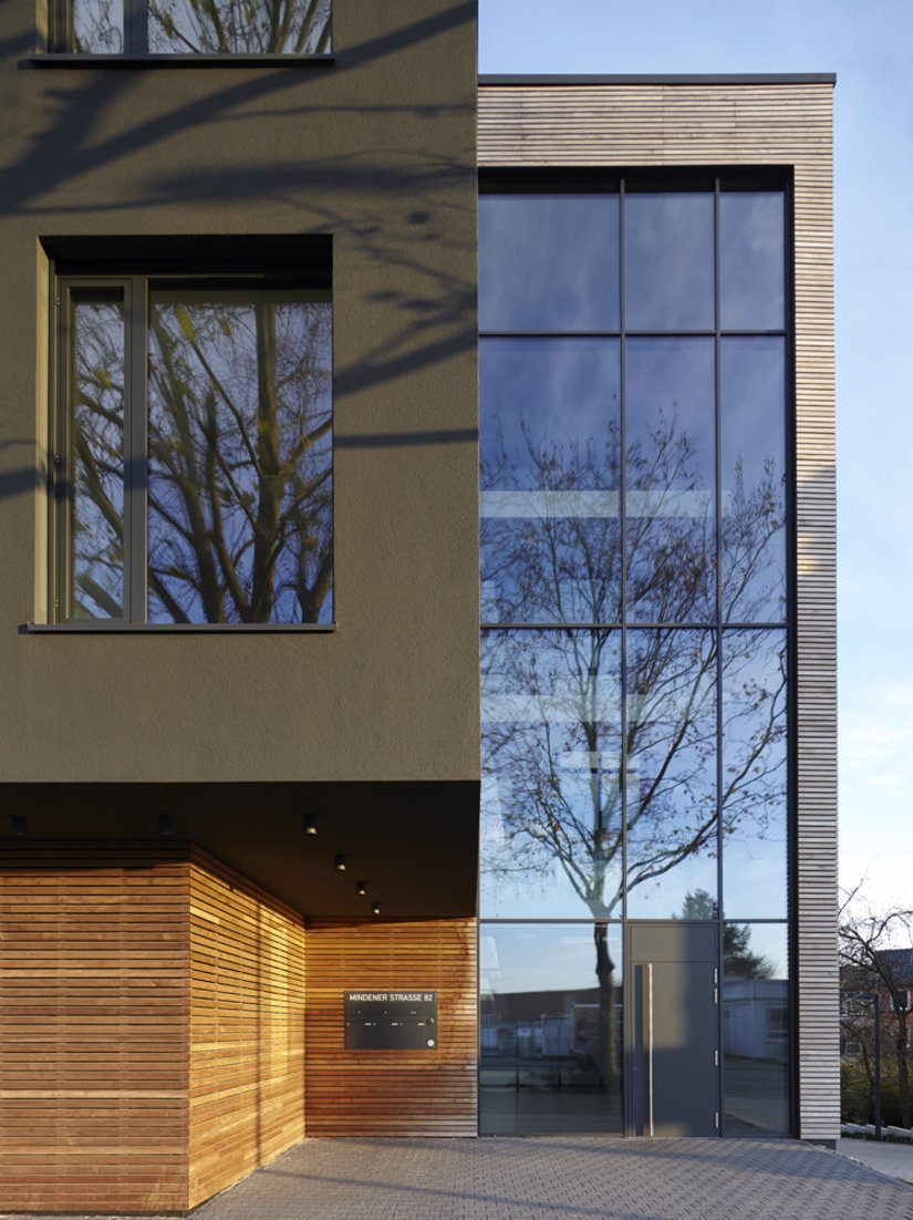 De delicate textuur van de horizontale houten lamellen doorbreekt het gewicht van de constructie uit gewapend beton en vormt een geslaagd contrast met de donkere, monochrome pleistergevel.