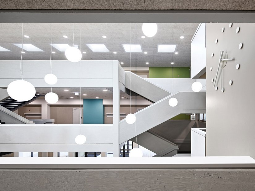Ook de nieuwe lift met zijn grote, minimalistische klok accentueert de hal als verticaal element.