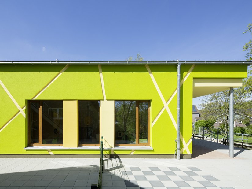 De scherpe, lichtgekleurde lijnen doorbreken de intense, groene kleur van de gevel.
